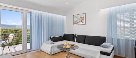 Een moderne woonkamer met een bank, een glazen salontafel en een balkon met uitzicht.