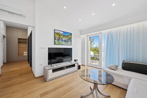 A modern living room with a flat-screen TV, a glass coffee table, a sofa, and a sliding glass door leading to an outdoor area. - Holiday Home Eros with Pool, Šibenik, Croatia (Šibenik)
