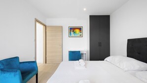 A modern hotel room with a bed, a blue armchair, a desk, and a painting on the wall. - Holiday Home Eros with Pool, Šibenik, Croatia (Šibenik)