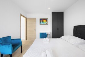 A modern hotel room with a bed, a blue armchair, a desk, and a painting on the wall. - Holiday Home Eros with Pool, Šibenik, Croatia (Šibenik)