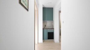 A narrow hallway leading to a kitchen with teal cabinets and a black dishwasher. - Holiday Home Eros with Pool, Šibenik, Croatia (Šibenik)