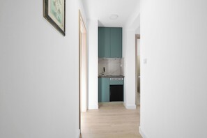 A narrow hallway leading to a kitchen with teal cabinets and a black dishwasher. - Holiday Home Eros with Pool, Šibenik, Croatia (Šibenik)