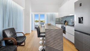 A modern kitchen with a stainless steel refrigerator, a dining area with a long table and chairs, and a view through a glass door. - Holiday Home Eros with Pool, Šibenik, Croatia (Šibenik)