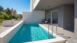 Un edificio moderno con piscina, asientos exteriores y vistas a edificios cercanos.