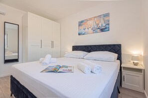 A hotel room with a bed, a nightstand, a bedside lamp, a painting of sailboats, a wardrobe, and a mirror. - Pool Villa Pomalo, Vodice, Croatia (Vodice)
