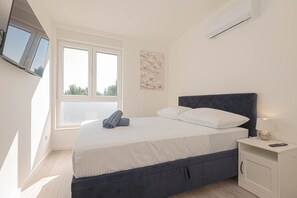 A bedroom with a bed, a nightstand, a TV mounted on the wall, and a window. - Pool Villa Pomalo, Vodice, Croatia (Vodice)
