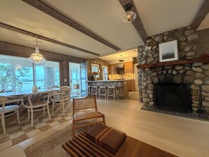 A spacious living area with a stone fireplace, a dining table with chairs, and a kitchen area with a stone accent wall.