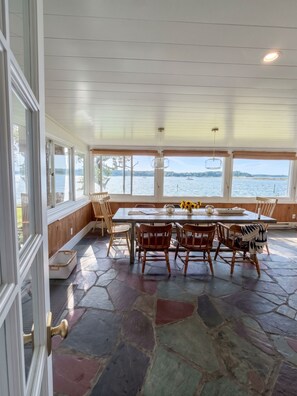 Comedor con vistas a un lago, suelo de piedra y mobiliario de madera.