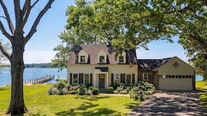 A two-story house with a garage, a dock, and a lake view.