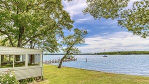 A lakeside property with a cabin, dock, and boat. - Shelter Island remodeled 1937 Cape Cod Waterfront with Deepwater Dock (Shelter Island)