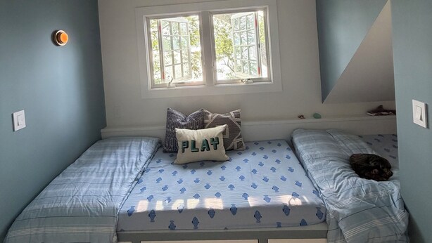 A bedroom with a bunk bed, a window, and a ceiling light fixture. - Shelter Island remodeled 1937 Cape Cod Waterfront with Deepwater Dock (Shelter Island)