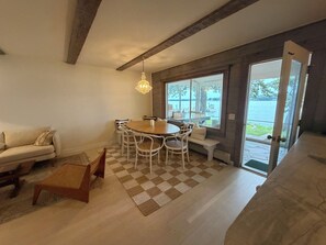 Ein Essbereich mit rundem Tisch und Stühlen, einer Couch und Seeblick durch große Fenster.