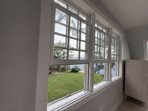 A room with a large window overlooking a grassy area and a body of water.