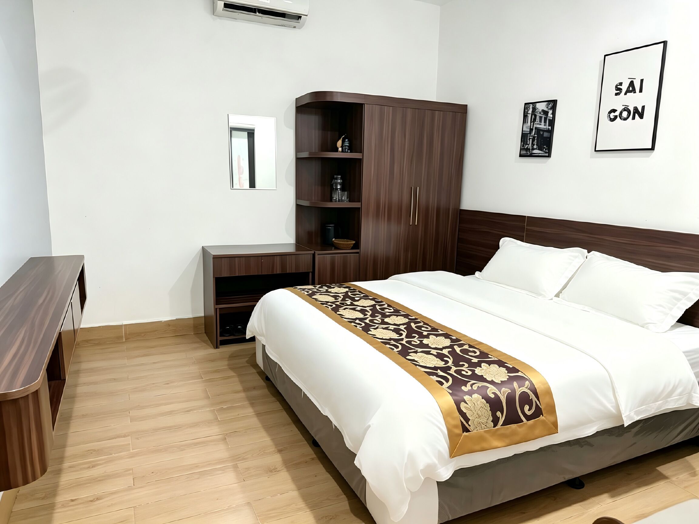 A hotel room with a bed, a wardrobe, a bedside table, and a mirror.