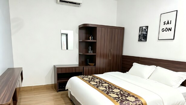 Una habitación de hotel con cama, armario, mesita de noche y espejo.