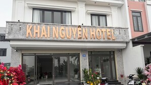Exterior del Hotel Khainguyen, con un letrero llamativo, entrada de vidrio y plantas en macetas.