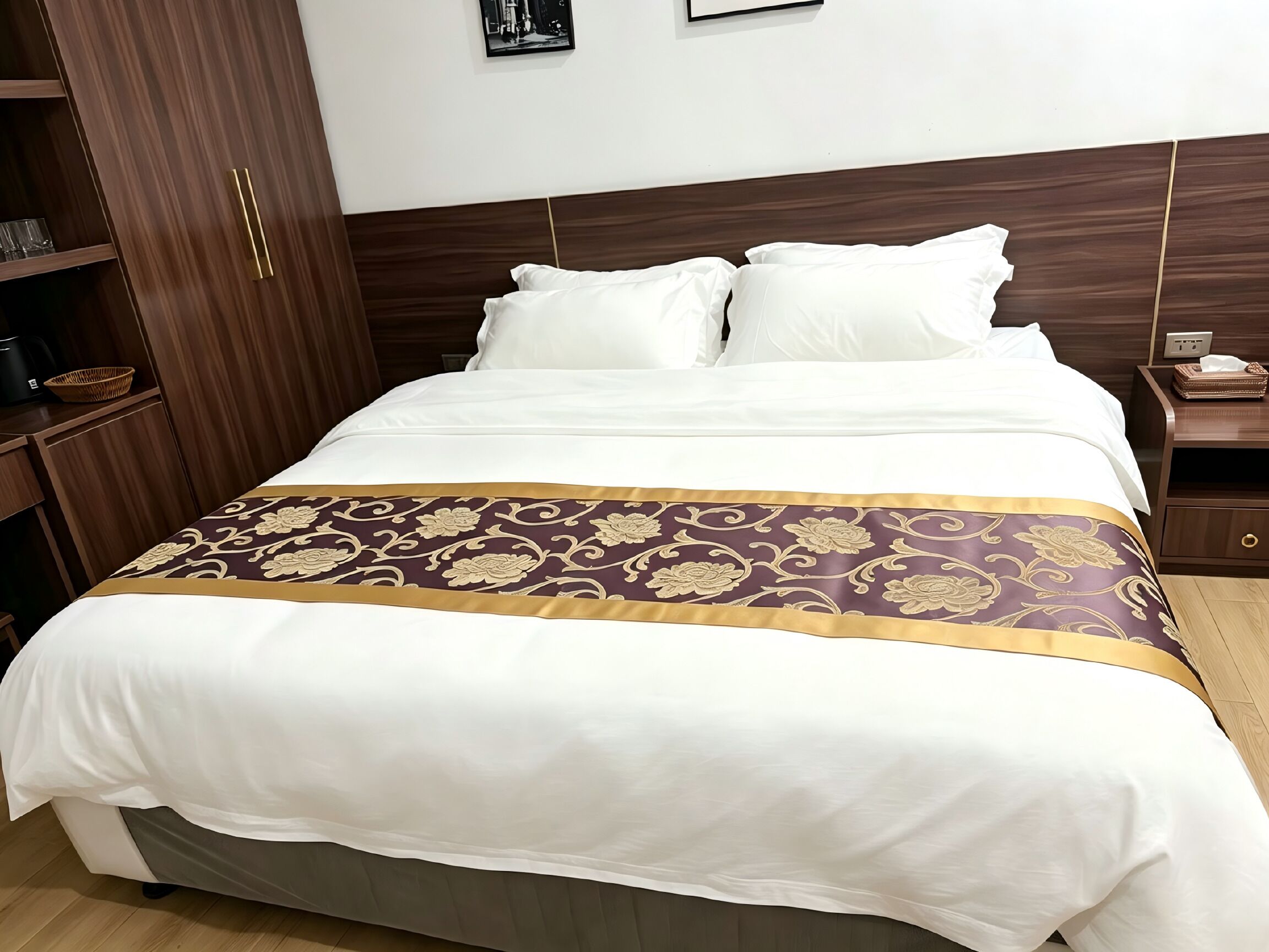 A hotel room with a bed, a nightstand, a wardrobe, and a wall-mounted picture.
