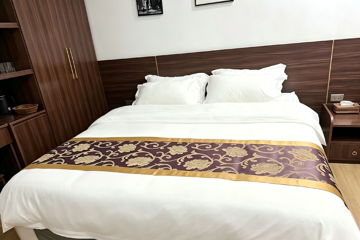 Quarto de hotel com cama, mesa de cabeceira, guarda-roupa e um quadro pendurado na parede.