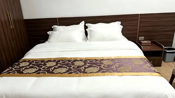 A hotel room with a bed, a nightstand, and a trash bin.