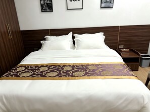 Una habitación de hotel con una cama, una mesita de noche y un cubo de basura.