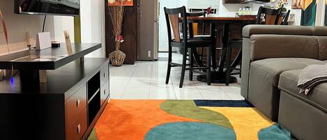Una sala de estar moderna con televisión, sofá y una alfombra colorida.