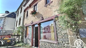 Ein Gebäude mit einer Stein-Fassade, großen Fenstern und einem Motorrad vor der Tür.