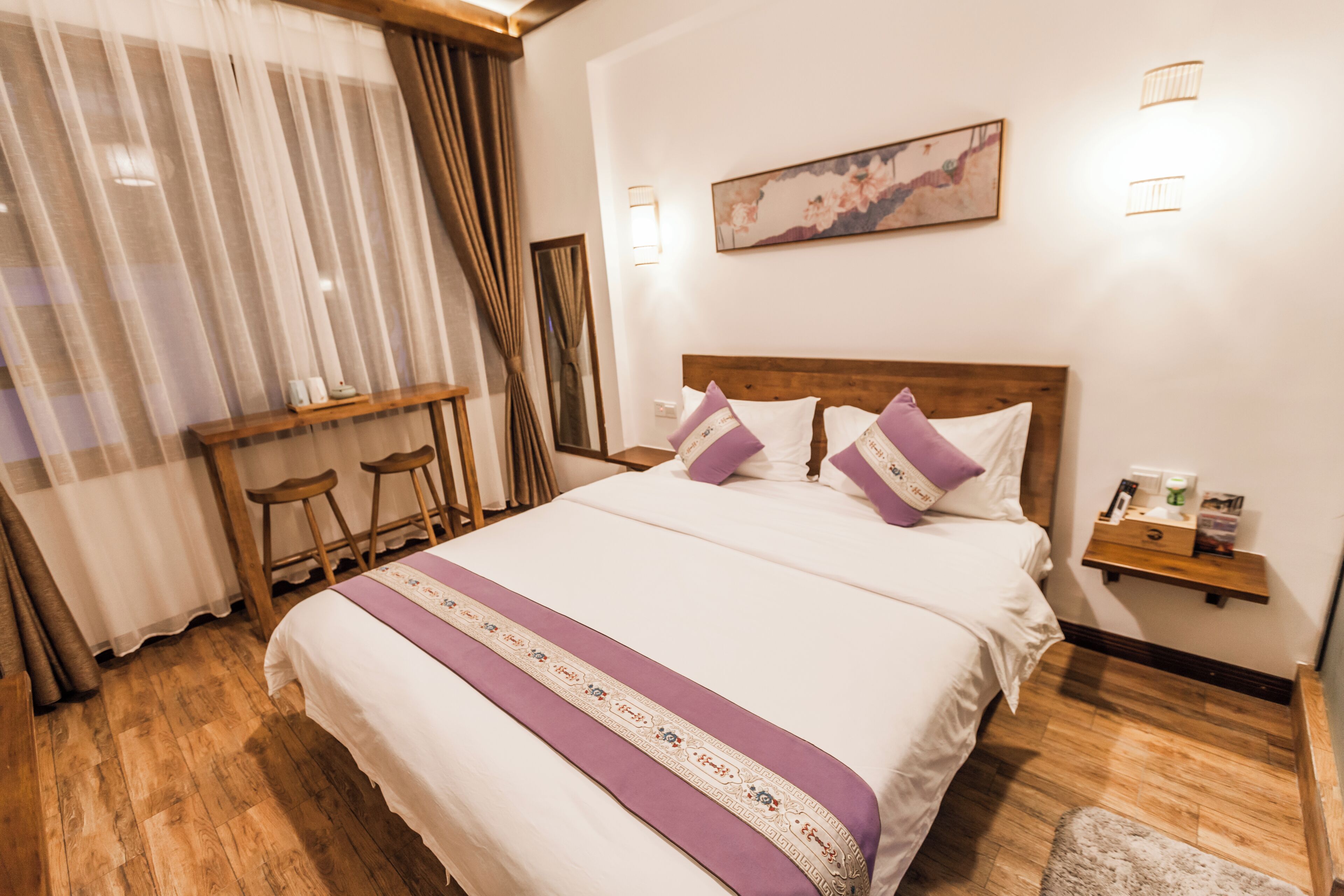 Un dormitorio ordenado con una cama grande, una mesita de noche de madera, una pequeña mesa y una silla.