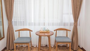 A room with two wooden chairs, a small round table with a tray, and sheer curtains. - zhangjiaije hexi inn (Zhangjiajie)