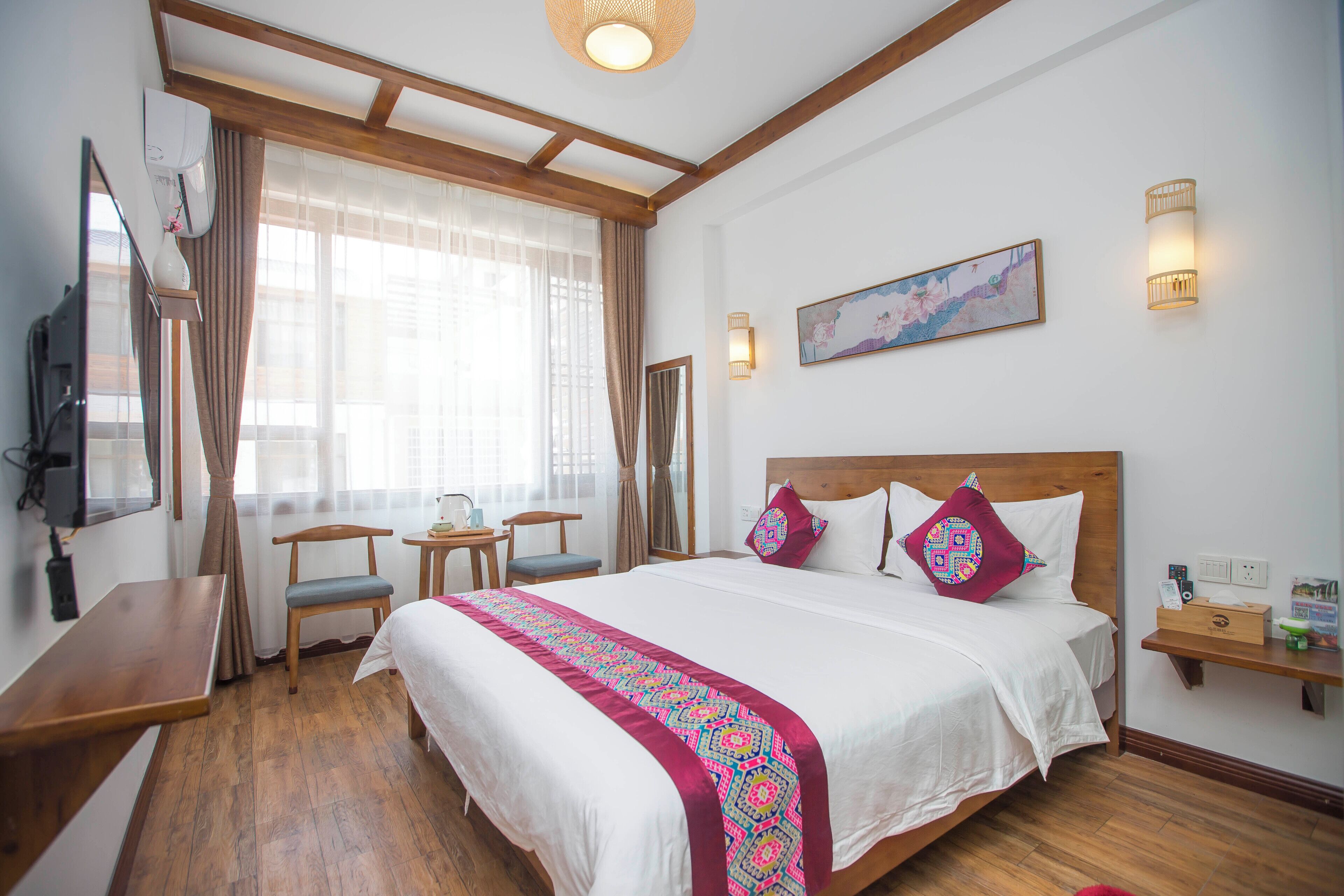 Habitación de hotel con una cama grande, un escritorio, una silla, un televisor y una ventana con cortinas.