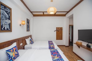 A hotel room with two beds, a television, a wooden door, and a ceiling light fixture. - zhangjiaije hexi inn (Zhangjiajie)