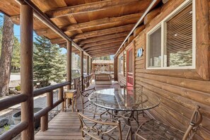Eine Holzhütte mit überdachter Veranda, einem Glastisch und Stühlen.