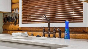 Eine Küche mit Holzrückwand, einem Spülbecken mit einem alten Wasserhahn und einer blauen Flasche Geschirrspülmittel.
