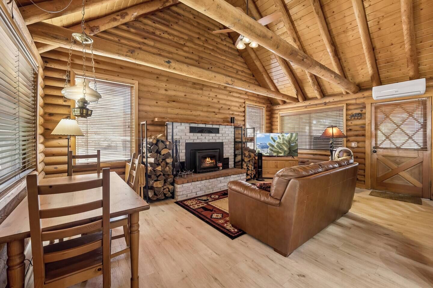A log cabin interior with a fireplace, wooden furniture, and a television.
