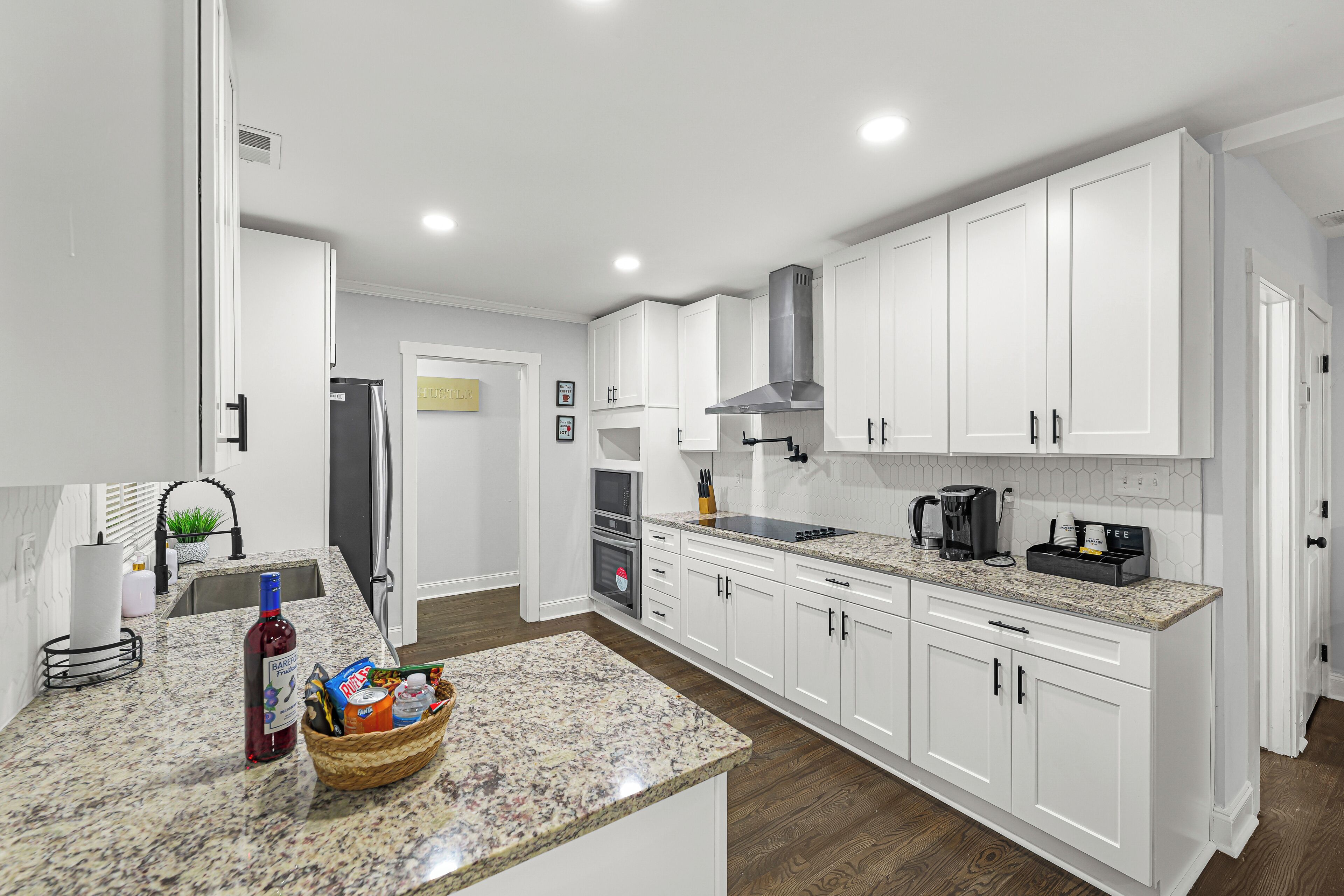 A modern kitchen with white cabinets, a granite countertop, and stainless steel appliances.