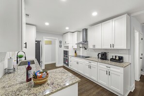 Une cuisine moderne avec des armoires blanches, un comptoir en granit et des appareils électroménagers en acier inoxydable.