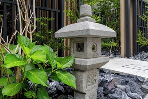 Un farol de piedra rodeado de follaje y rocas.