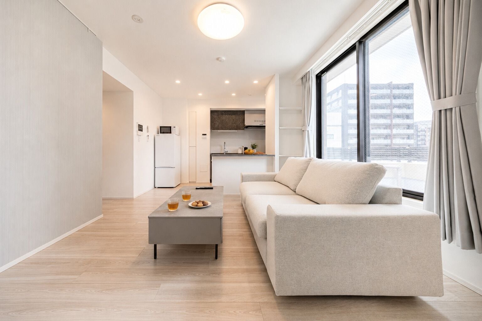 A modern living room with a sofa, coffee table, and kitchen in the background.