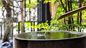 Een traditioneel Japans waterkunstwerk met een bamboe-schep die water in een houten kom giet.