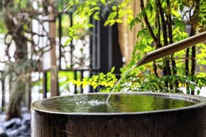 Una fuente tradicional japonesa con una cuchara de bambú vertiendo agua en un cuenco de madera.