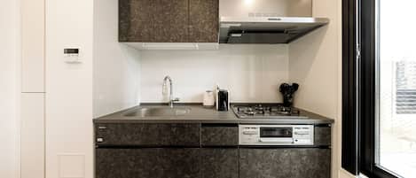 Una cocina funcional con gabinetes oscuros, un lavamanos de acero inoxidable, estufa y horno empotrado.