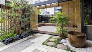 Een moderne buitenruimte met een houten terras, een groot waterpartij en diverse planten.