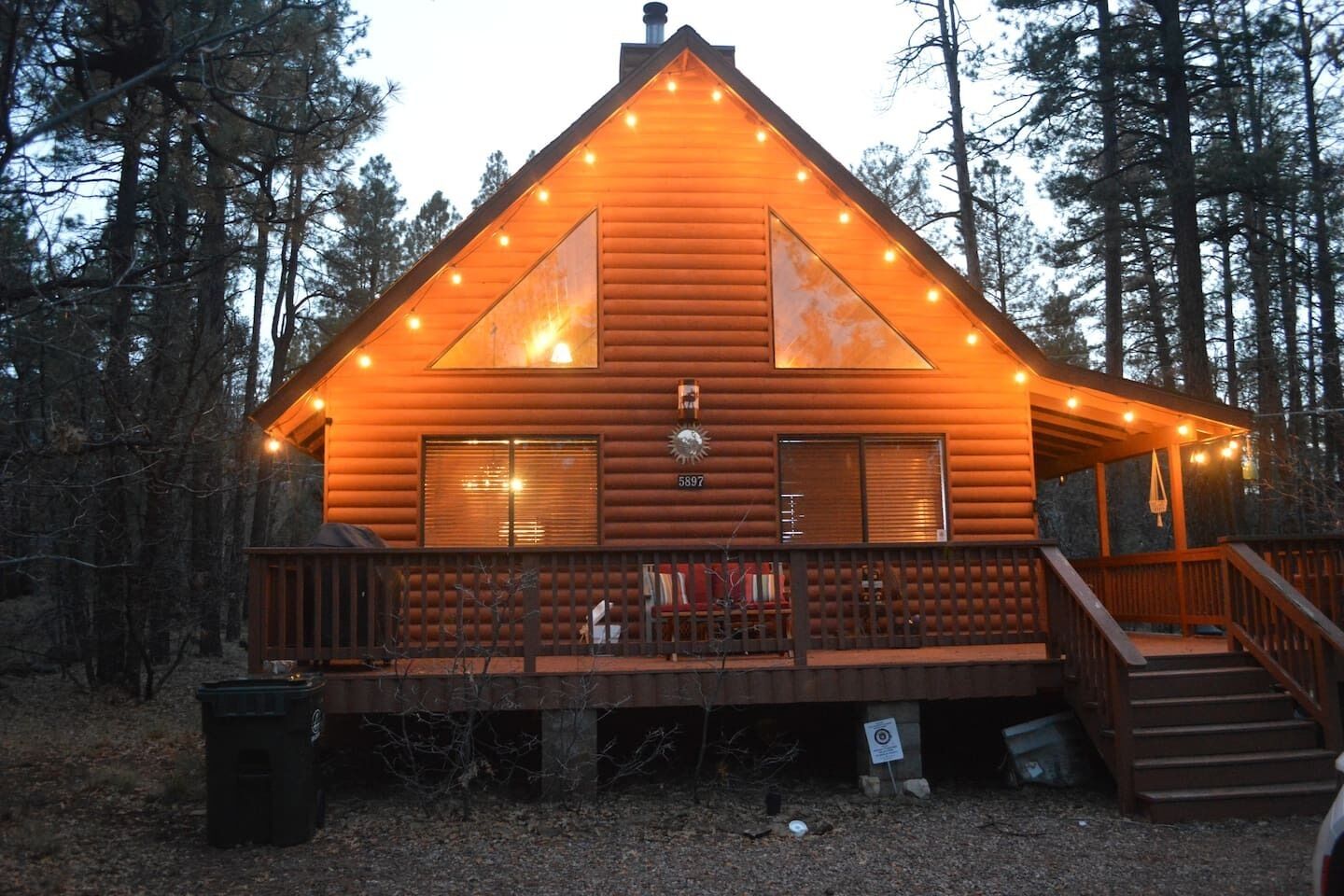 A log cabin with a porch, a chimney, and a deck.