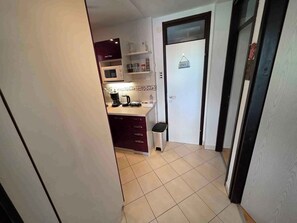 A narrow hallway with a kitchen area featuring a microwave, coffee maker, and cabinets. - Holiday apartment apartment with air conditioning and wifi (Klenovica)