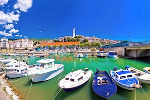 A marina with various boats docked, a bridge, and buildings in the background. - Holiday apartment apartment with air conditioning and wifi (Klenovica)