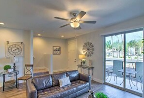A living room with a leather sofa, a ceiling fan, a clock, and a dining area with outdoor seating. - Modern Farmhouse Mesa Retreat (Mesa)
