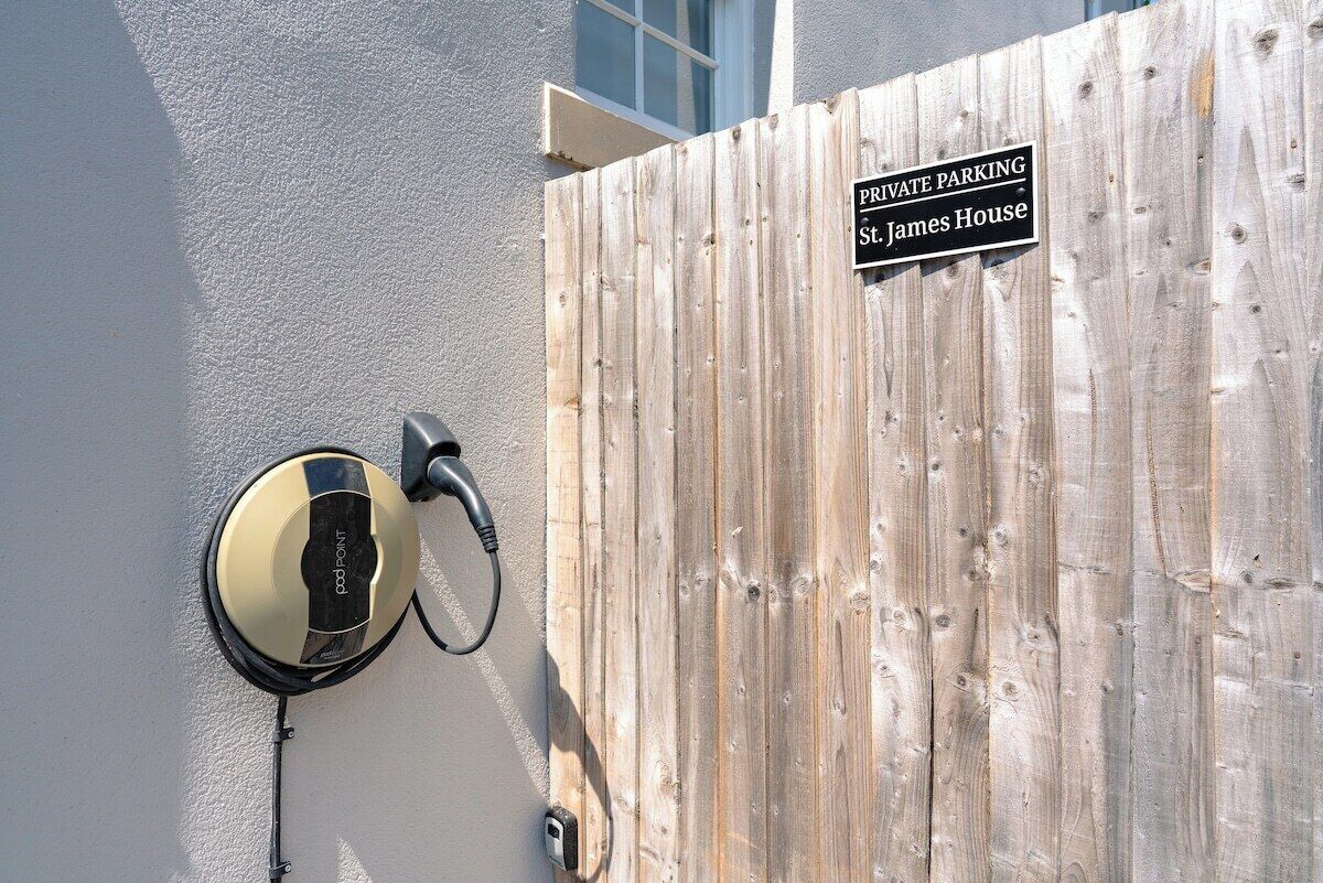 Un panneau indiquant un stationnement privé, fixé à une clôture en bois, un interphone avec un bouton-poussoir et une caméra de surveillance.