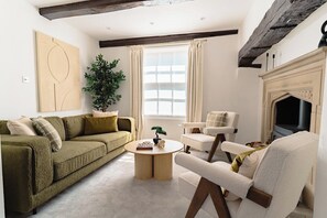 A living room with a sofa, armchair, round coffee table, and a fireplace.
