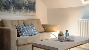 A modern living room with a sofa, a coffee table, decorative items, and a painting on the wall. - St James House Timeless Comfort Central Congleton (Congleton)