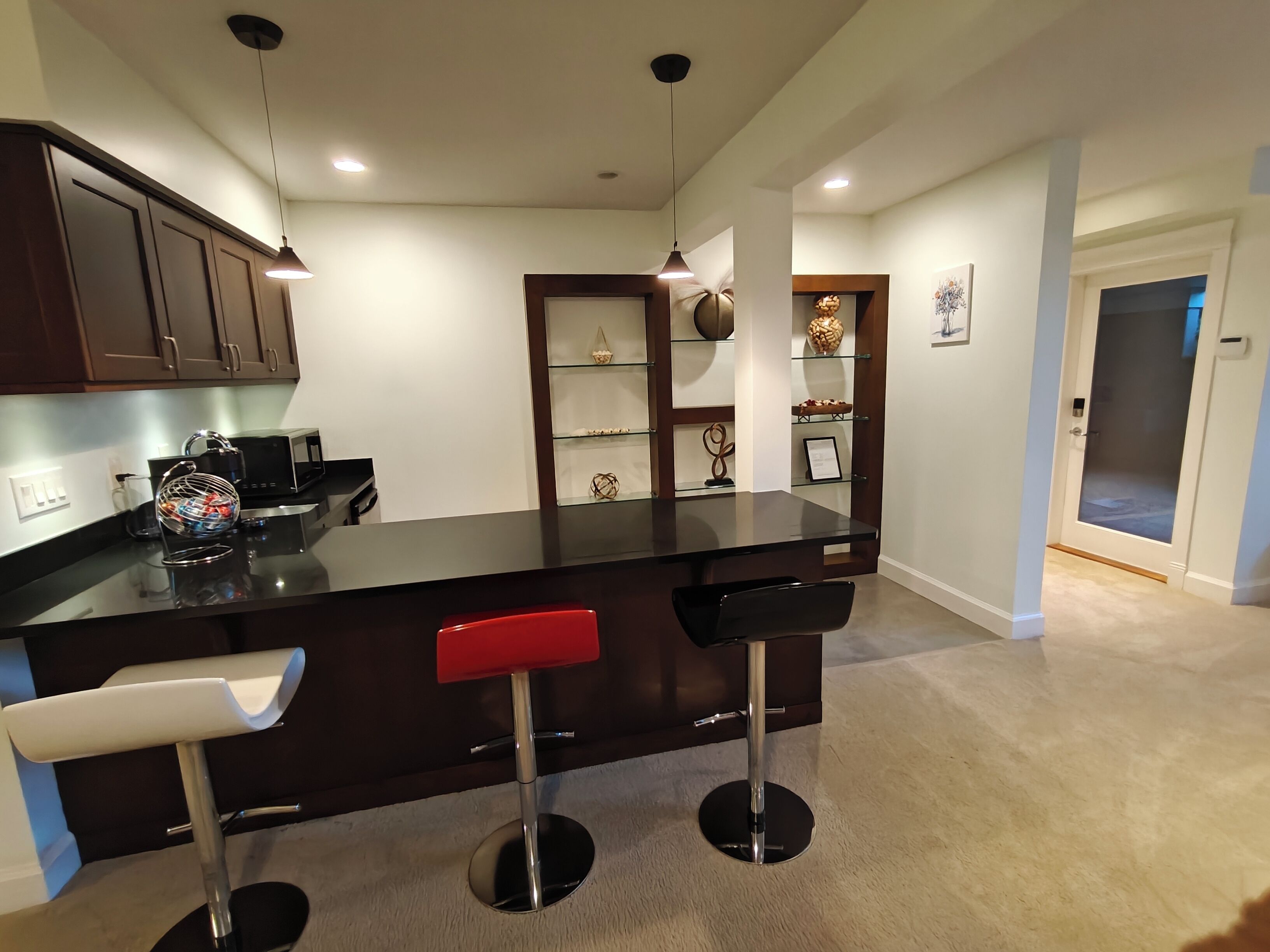 A modern kitchen with dark cabinetry, a central island with bar stools, and pendant lighting.
