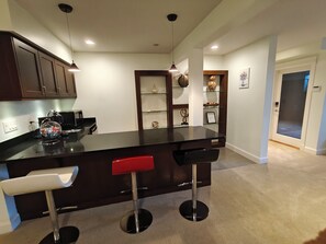A modern kitchen with dark cabinetry, a central island with bar stools, and pendant lighting.